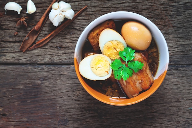 Stewed eggs and pork or eggs and pork in brown sauce in bowl with spices on wooden table