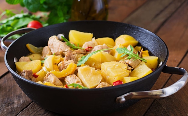 Photo stewed potatoes with meat and vegetables in a roasting tin on a wooden background