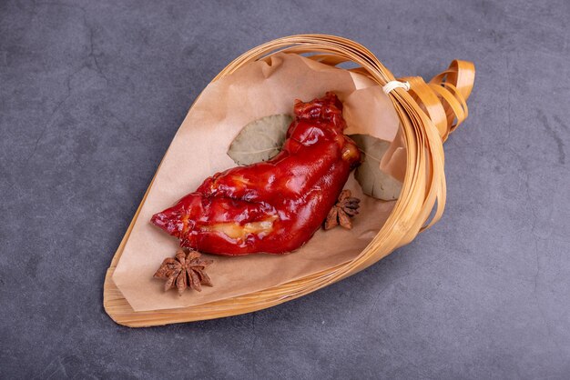 Photo stewed red pigs feet are in a bamboo container against a dark background