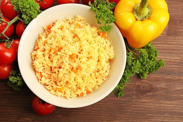 Stewed rice with a carrot on a plate over wooden background