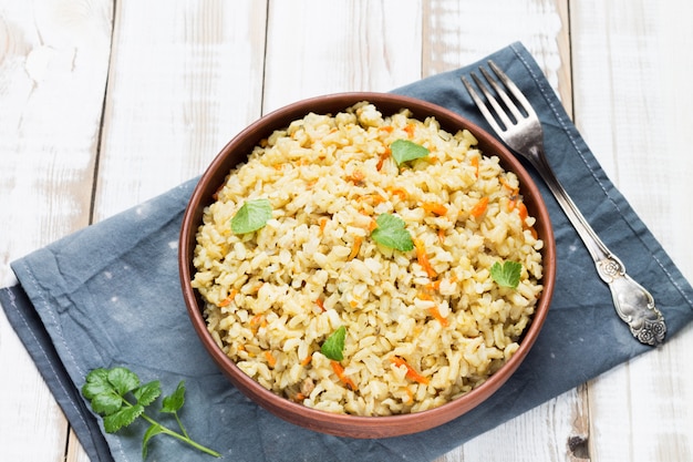 Stewed side dish of brown rice in a bowl on a gray linen napkin.