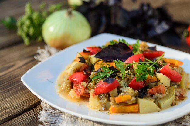 Stewed vegetables in a white bowl on wooden table