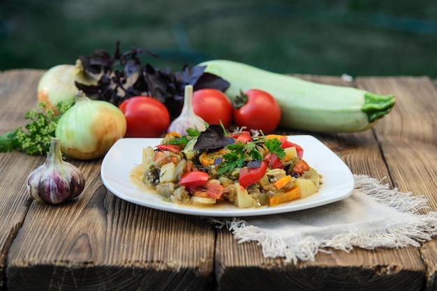 Stewed vegetables in a white bowl on wooden table