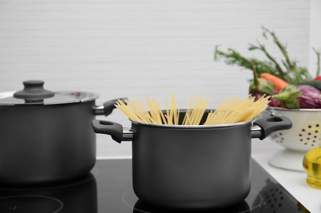 Stewpan with spaghetti on electric stove in kitchen