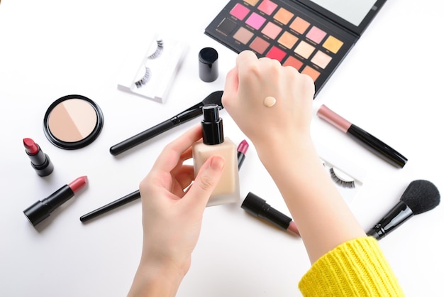 Stichting in handen van de vrouw. professionele make-upproducten met cosmetische schoonheidsproducten, foundation, lippenstift, oogschaduw, wimpers, borstels en gereedschap.