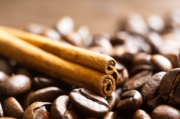 A stick of cinnamon lies on the roasted coffee beans closeup