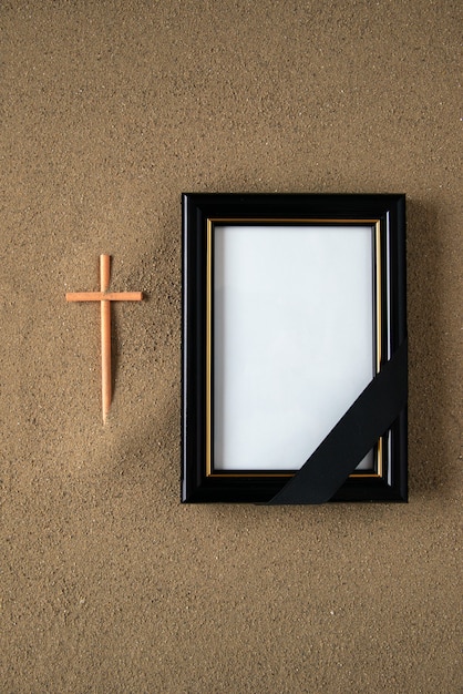 Stick cross with picture frame on the sand