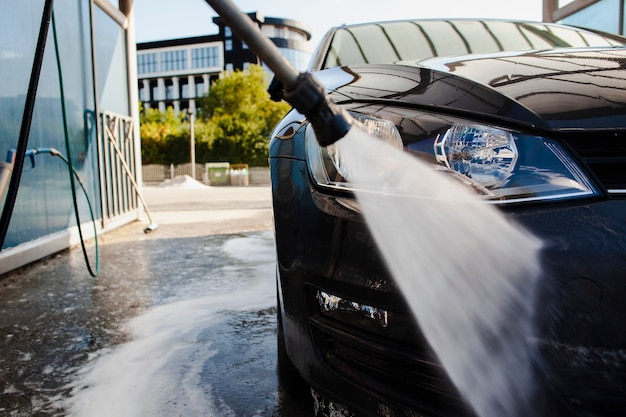 Foto stick lavare la parte anteriore di un'auto con acqua