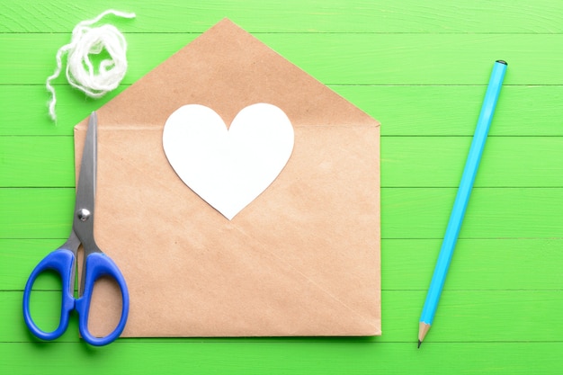 Sticker in de vorm van een hart met een envelop op groene houten achtergrond
