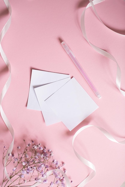 Stickers for writing with a pen on a pink background next to a white ribbon and white flowers