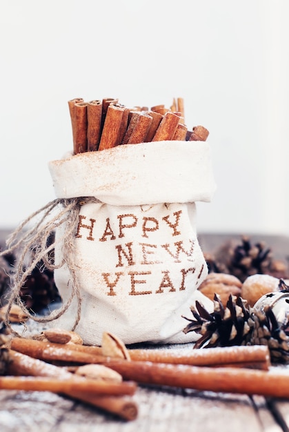 Sticks of Cinnamon in Linen Bag with Embroidery Happy New Year Light  Background. Toned 