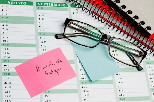 Sticky note and eyeglasses on a calendar with a handwritten note