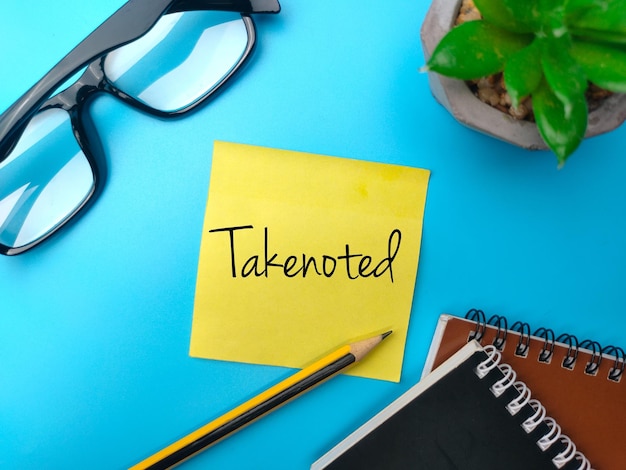 青の背景に「Takenoted」という単語が付いた付箋と鉛筆