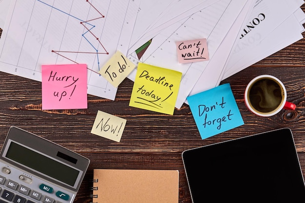 Sticky notes with coffee cup and calculator top view brown wooden desk background