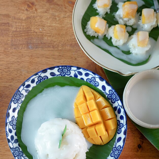 Sticky Rice with Ripe Mango in Coconut Milk Authentic Thai desserts on a wooden table