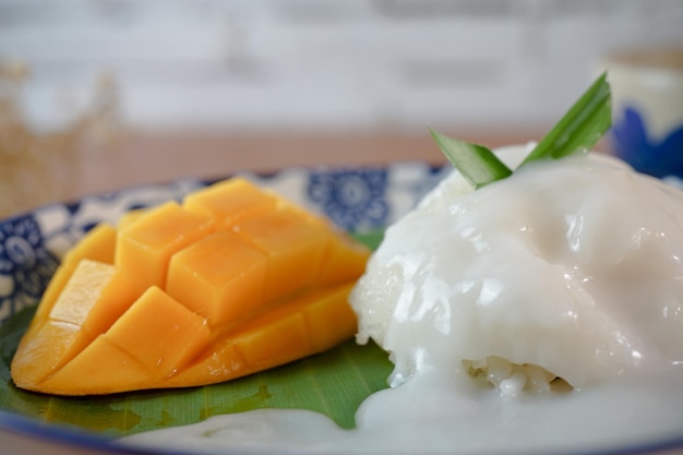 写真 もち米とココナッツミルクの熟したマンゴー木製テーブルの上の本物のタイのデザート