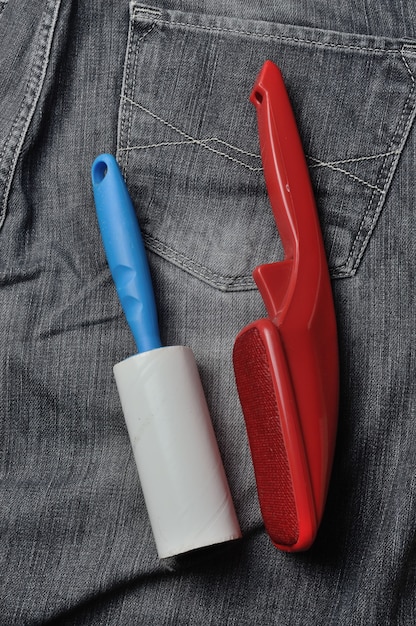 A sticky, roller-coiled garment brush rests on dark jeans.