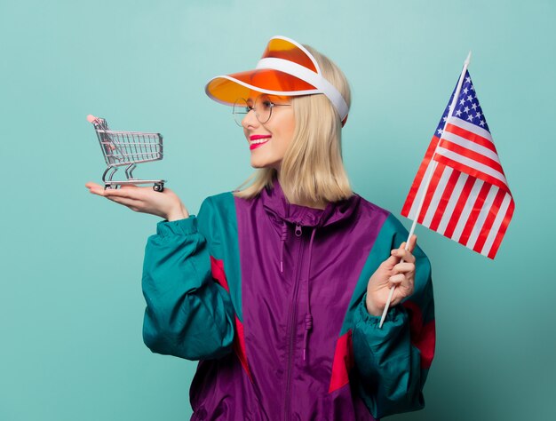 Stijl blonde vrouw in jaren 90 sport pak met winkelwagen en vlag van de Verenigde Staten