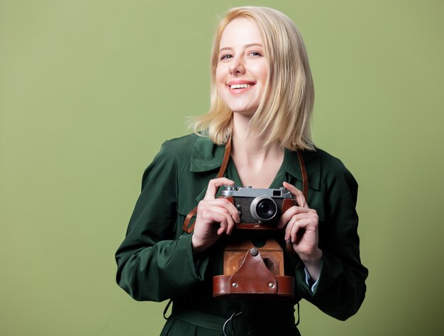 Stijl blonde vrouw in mantel met camera