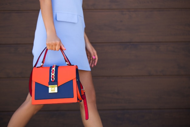 Stijlvol blauw met oranje leren damestas. Het meisje houdt in haar hand. Zak van dichtbij. Detailopname.
