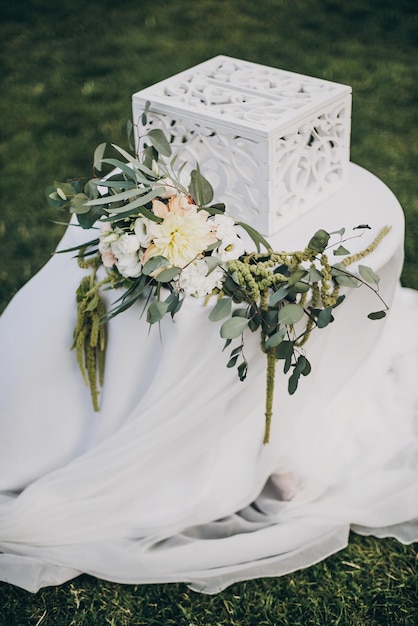 Stijlvol bloemendecor van bruiloft gangpad rozenblaadjes op gras en moderne houten kist voor geschenken van gasten voor bruidspaar Geschenkdoos op tafel met bloemstuk