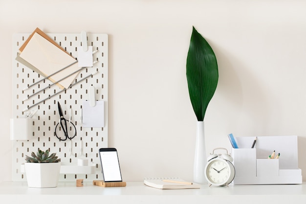 Stijlvol bureauinterieur met witte tafelachtergrond met plant en bladeren. Modern kantoor aan huis interieur