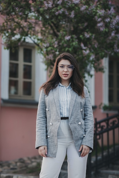 Stijlvol elegant meisje lopen op straat, jas en witte broek dragen, herfst lente seizoen.