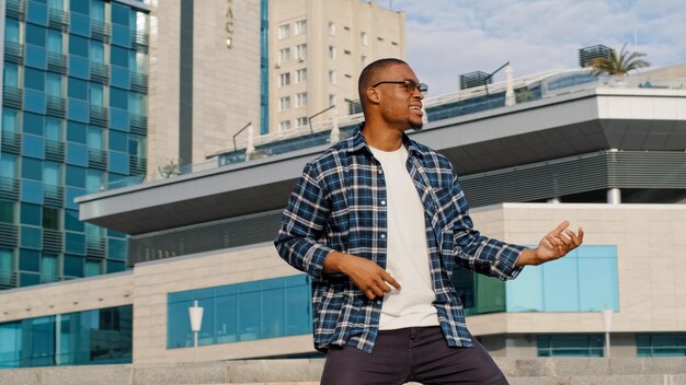 Stijlvol, gelukkig, vrolijk, Afro-Amerikaanse kerel die een liedje zingt, doet alsof hij gitaar speelt en van muziek geniet.