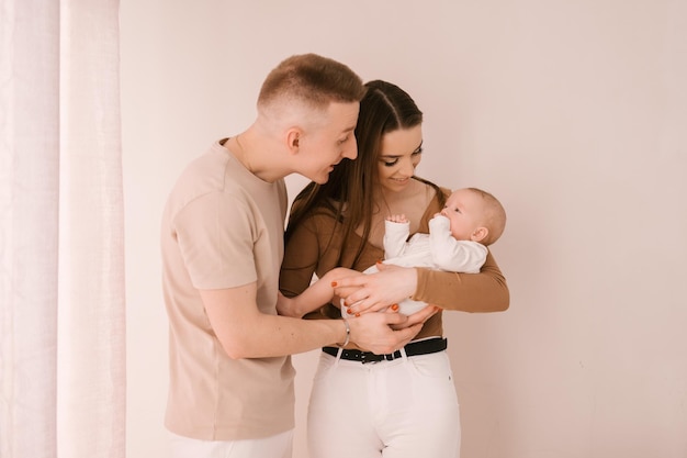 Stijlvol jong gezin gefotografeerd met een kleine mooie baby Het gezin drukt liefde en ontzag uit voor elkaar Familie- en opvoedingsconcept