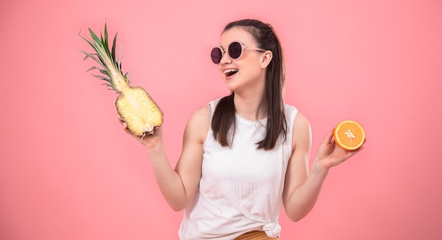 Stijlvol jong meisje in zonnebril glimlacht en houdt fruit. zomer vakantie concept.