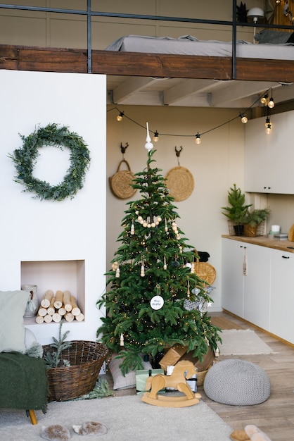 Stijlvol kerstdecor in een Scandinavisch landhuis in beige tinten. Open haard en kerstboom in de woonkamer