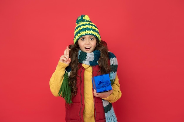 Stijlvol kind in gebreide zorg voor de gezondheid in het koude seizoen met een geschenkdoos voor de winterverkoop van het nieuwe jaar