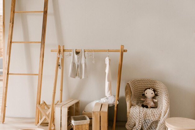 Stijlvol kinderkamerinterieur in Scandinavische stijl met houten hanger en babykleertjes