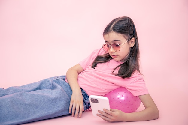 Stijlvol meisje met een smartphone op een roze achtergrond