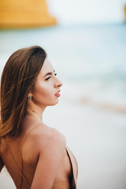 stijlvol meisje permanent met vliegende haren uit de wind bij zonsondergang op het strand en de oceaan