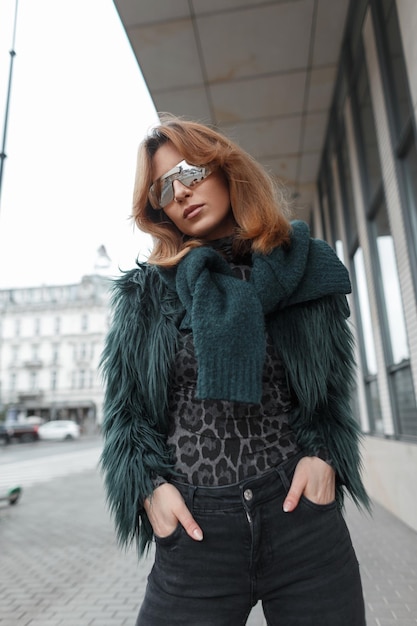 Foto stijlvol mooi mode vogue model meisje met zonnebril in modieuze kleren met een shaggy bont jas met een trui poseert in de stad