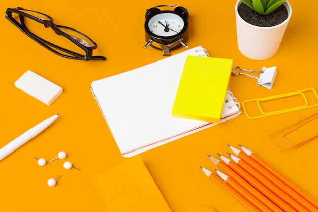 Stijlvol rommelig geel bureau met verschillende bovenaanzicht van briefpapier