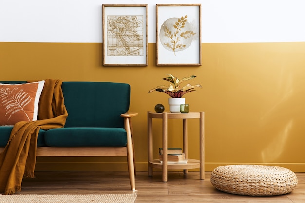Stijlvol Scandinavisch interieur van woonkamer met design groen fluwelen bank, gouden poef, houten meubilair, planten, tapijt, kubus en posterframes.