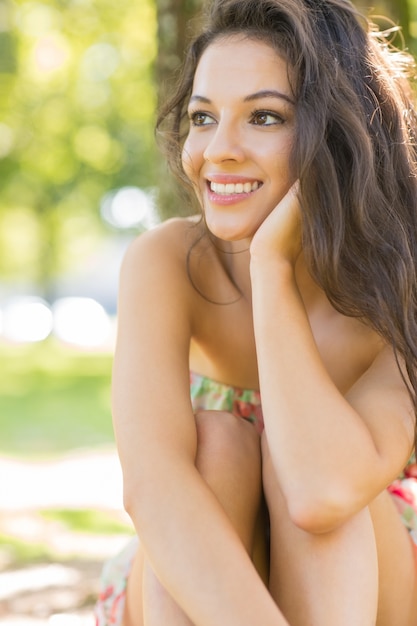 Stijlvolle aantrekkelijke brunette zittend onder een boom