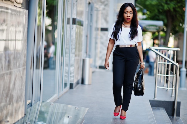 Stijlvolle Afro-Amerikaanse zakenvrouw met handtas in de straten van de stad
