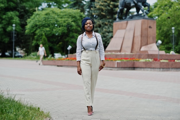 Stijlvolle Afro-Amerikaanse zakenvrouw op broek met jarretel en blouse poseerde buiten