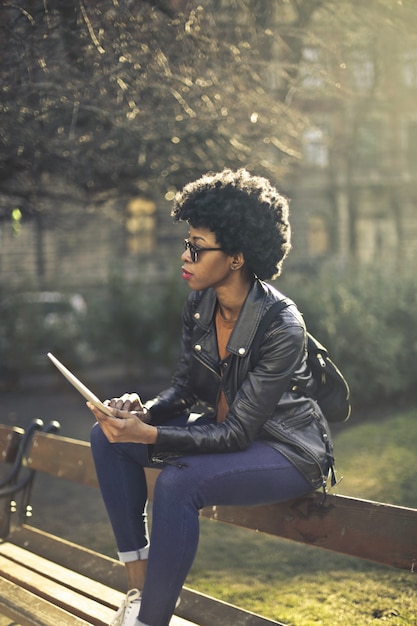 Stijlvolle Afro-vrouw in een park met een tablet