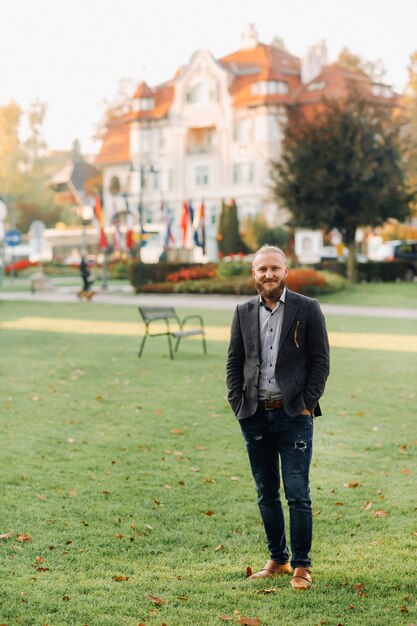 Stijlvolle bebaarde man in een pak in het park van een Oostenrijkse stad.