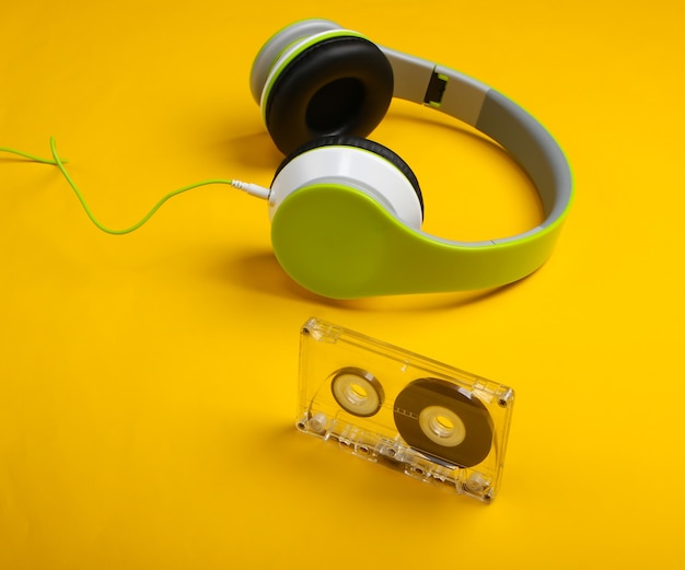 Stijlvolle bedrade stereohoofdtelefoon met audiocassette op geel oppervlak