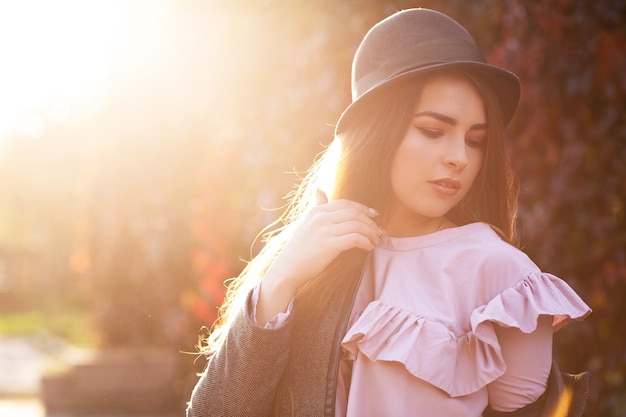 Stijlvolle brunette gebruinde vrouw met natuurlijke make-up die hoed en jas draagt. Ruimte voor tekst