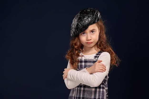 Stijlvolle brunette jongen poseert in studio op een zwarte achtergrond. Kindermode.