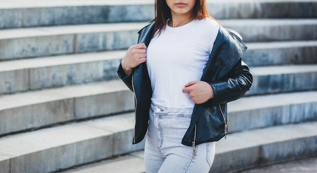 Stijlvolle brunette meisje met witte t-shirt en bril poseren tegen straat stedelijke kledingstijl