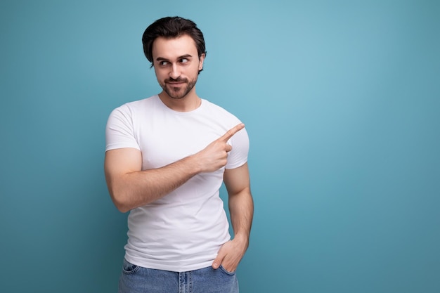 Stijlvolle brutale sterke brunette man in een wit t-shirt met spieren wijst een vinger naar de zijkant