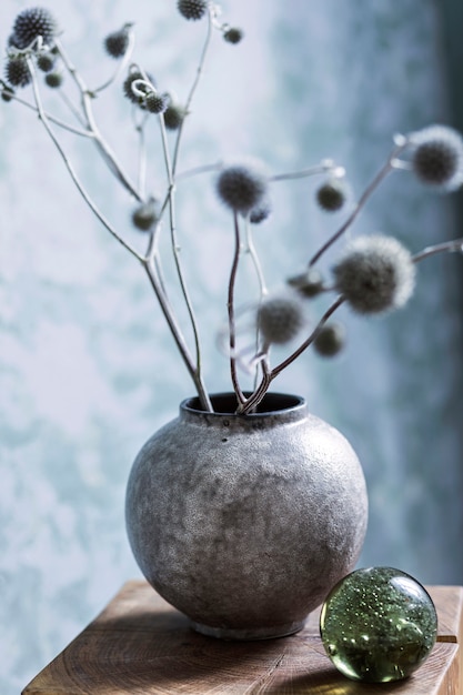 Stijlvolle compositie van creatieve en gezellige interieurdetails in de woonkamer met gedroogde planten in grijze vaas