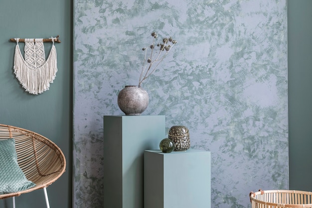 Stijlvolle compositie van creatieve en gezellige interieurdetails van de woonkamer met rotan fauteuil en gedroogde planten in grijze vaas. Eucalyptus muren.